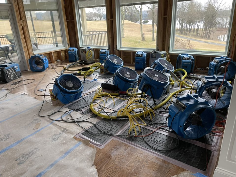 Industrial air movers and dehumidifiers drying a flooded residential room